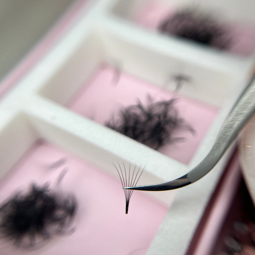 Eyelash extension tool with false eyelashes on a pink background