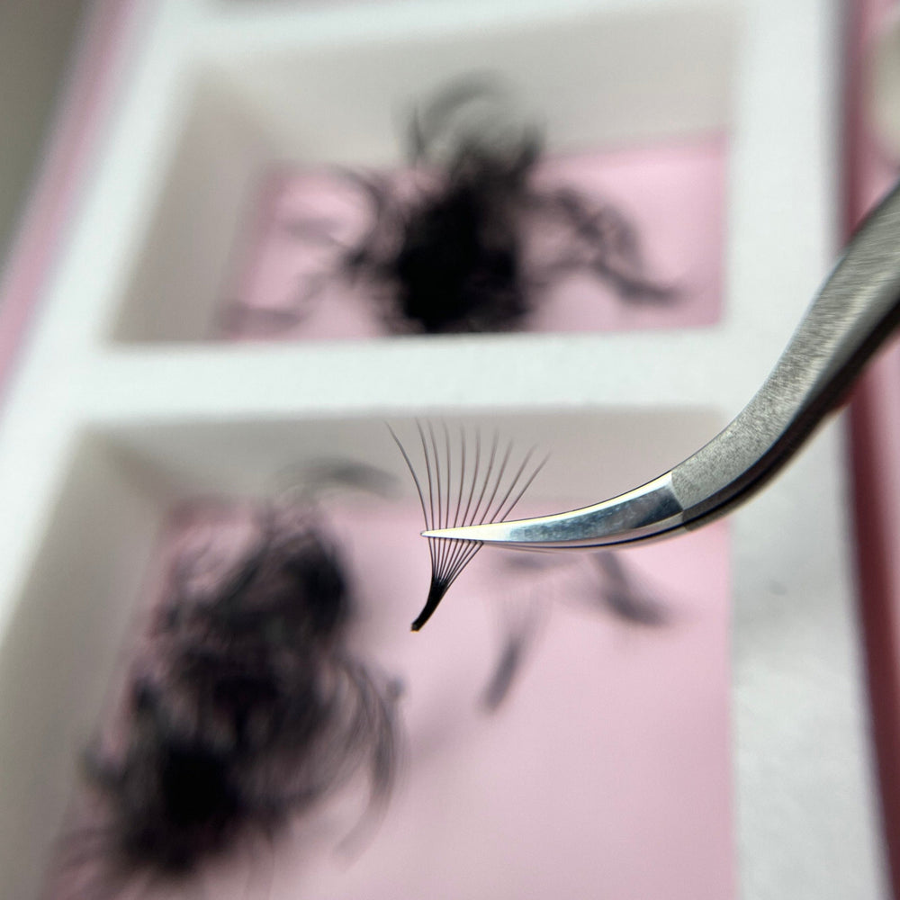Eyelash extension being applied with tweezers in front of a mirror.