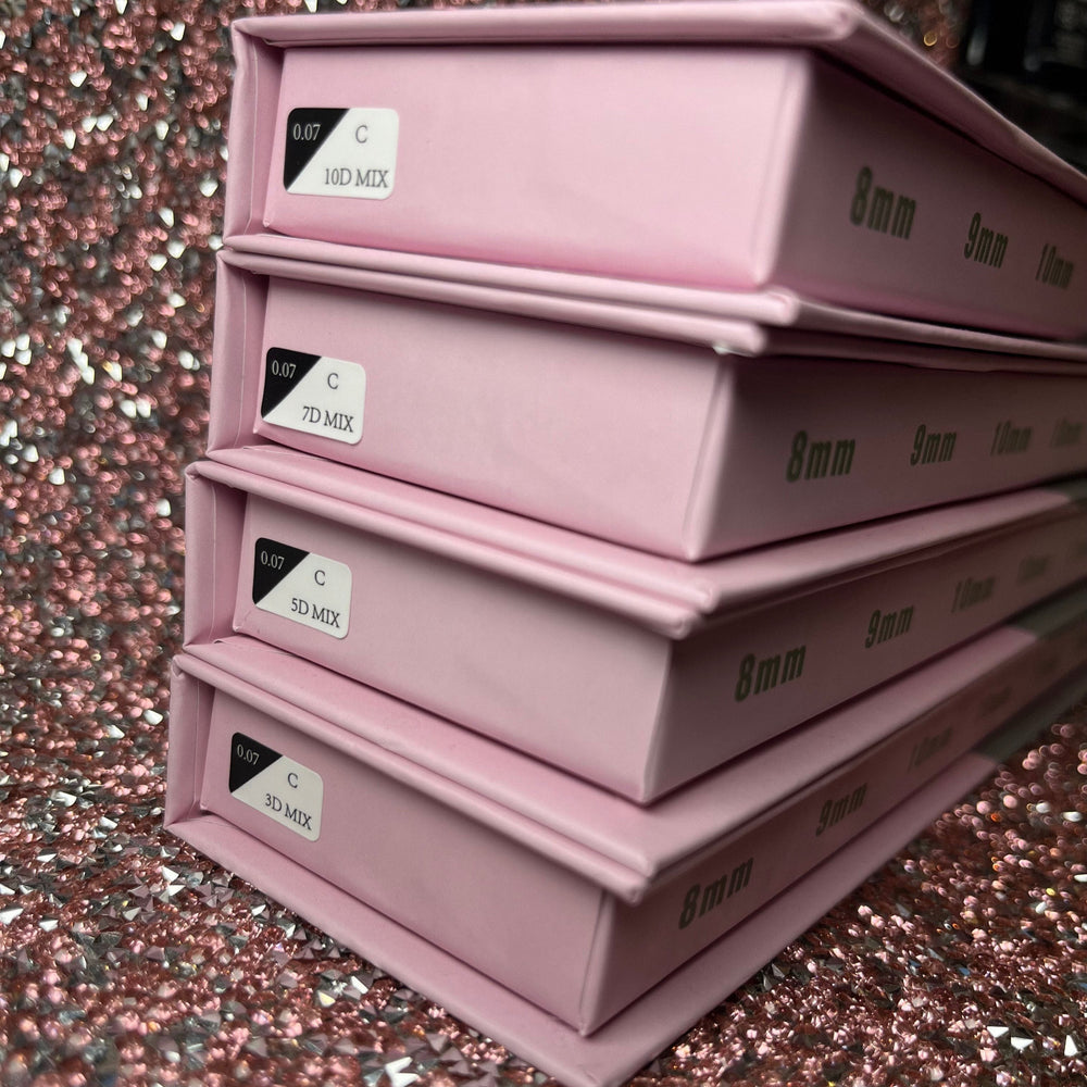 Stack of pink boxes of loose eyelash extensions volume promade fans with labels on a glittery pink background