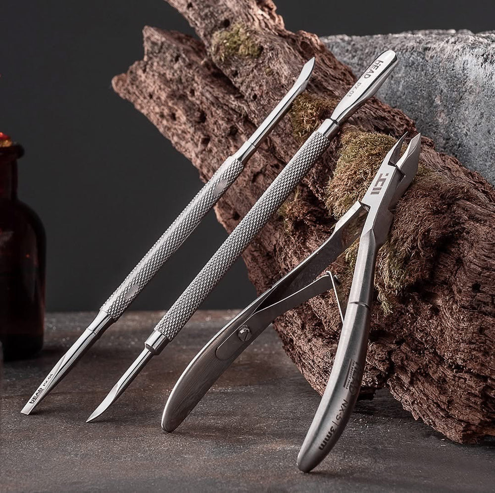 Professional stainless steel cuticle pusher with a textured handle and cuticle nipper for manicure and pedicure on a textured surface with a dark background