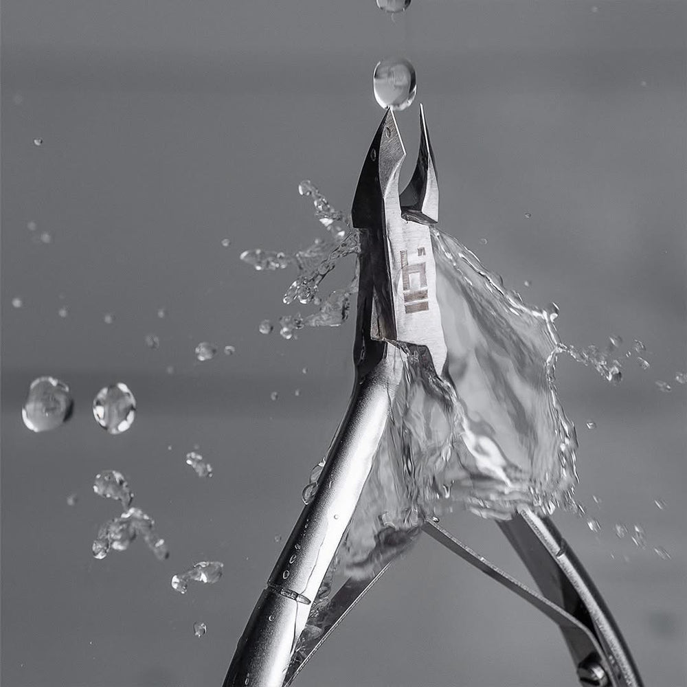 Metal pliers with a clear plastic bag being stretched by water droplets on a gray background